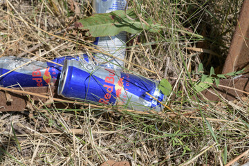 Fototapeta premium pile of discarded Red Bull energy drink cans in the grass, Toronto