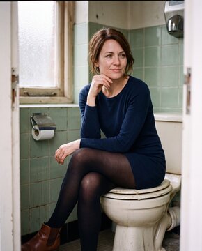 Nachdenkliche Frau sitzt in einem alten Badezimmer auf dem Toilettendeckel