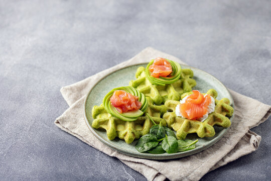 Delicious vegan spinach waffles with salmon fish in plate.
