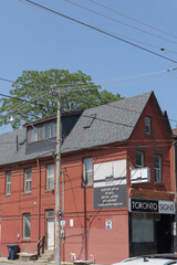 Fototapeta premium wide view of historic house and signage outside Toronto Signs, a sign shop, located at 302 Broadview Av
