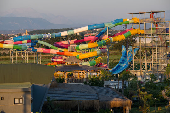Side, Turkey, July 25, 2026: Colourful water park slides ad the sunset with tropical landscaping, travel holiday leisure background