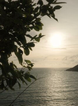 A vast ocean landscape at twilight, with sunlight reflecting off the water's surface, creating a sparkling spectacle