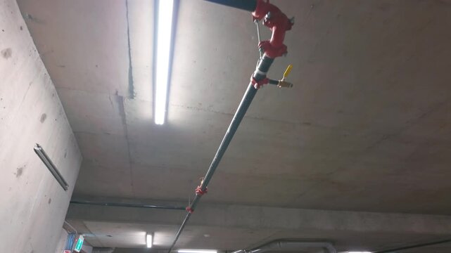 Industrial fire sprinkler pipe installation on concrete ceiling with LED strip lights