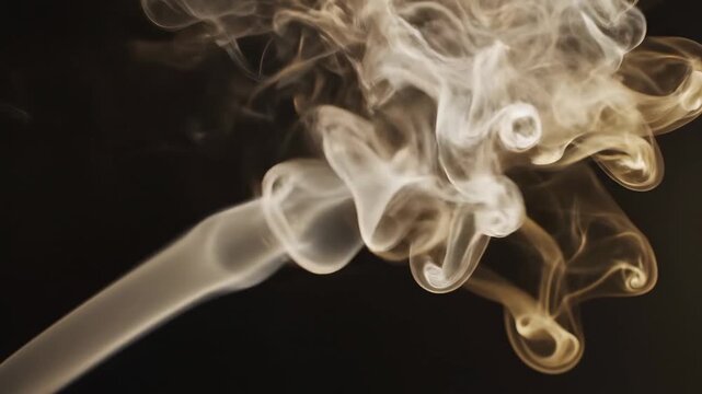 White smoke curls and rises in the air against a dark background. The movement creates interesting shapes as it drifts upwards slowly