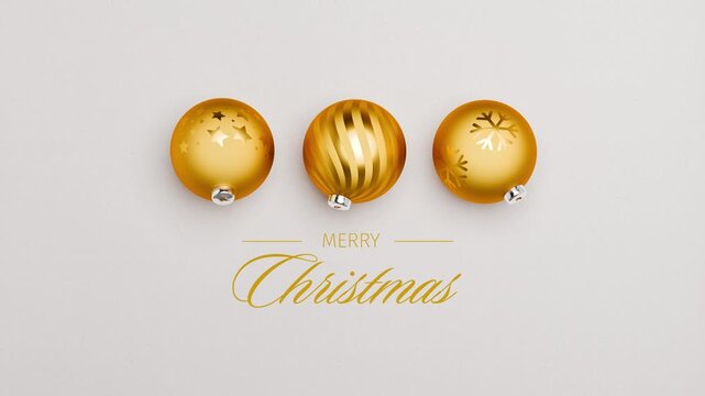 Three golden christmas baubles spinning on a paper surface. English language Merry Christmas messages appearing and dissolving. Loopable video