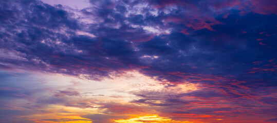 Fototapeta premium Stunning Sunset Sky with Colorful Clouds and Golden Horizon,A breathtaking view of a vibrant sunset sky filled with dramatic golden, orange, and pink clouds scattered across a serene blue atmosphere,