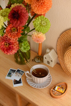 Cozy autumn still life high angle view with cup of tea, polaroid photos and flower bouquet on wooden table