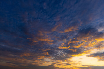 Fototapeta premium Stunning Sunset Sky with Colorful Clouds and Golden Horizon,A breathtaking view of a vibrant sunset sky filled with dramatic golden, orange, and pink clouds scattered across a serene blue atmosphere,