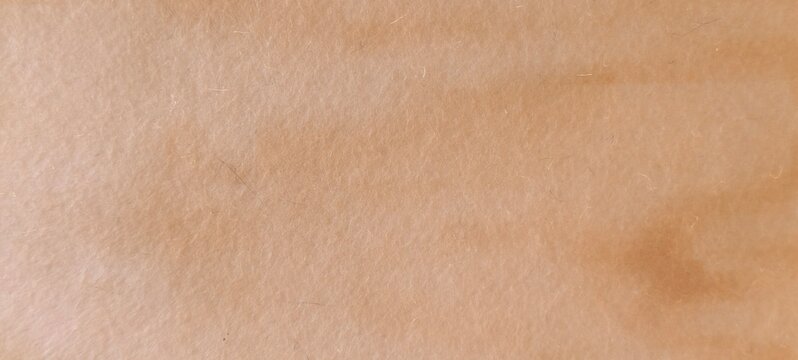 Macro view of a soft beige textured surface with faint fibers and subtle tonal variations. The natural fibrous appearance suggests paper, fabric, or organic material, offering a neutral background.