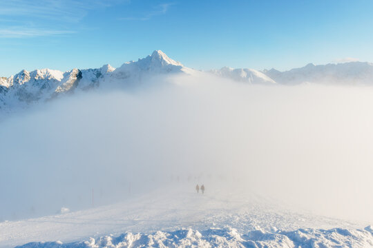 Winter mountain ski slope in thick fog with silhouettes of people in Zakopane, Poland