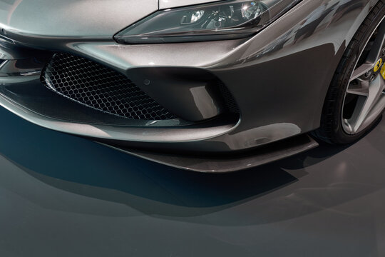 Close up showcases the front end of a gray Ferrari F8 Tributo. Details of the front bumper, grill, headlight, and wheel are prominent in this sleek, modern design. Katowice, Poland, 14.06.2019
