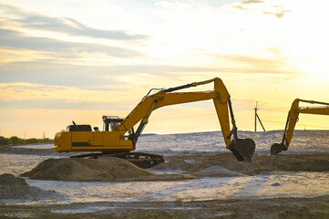 Excavator working in a sandy quarry, digging and moving sand. Industrial construction scene showing heavy machinery operating at a sand extraction site. © senssnow