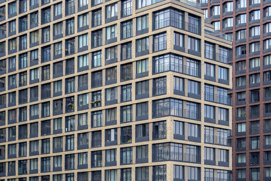 Angular skyscraper facade with glass balconies as a geometric pattern. Residential apartment buildings for real estate backdrop.
