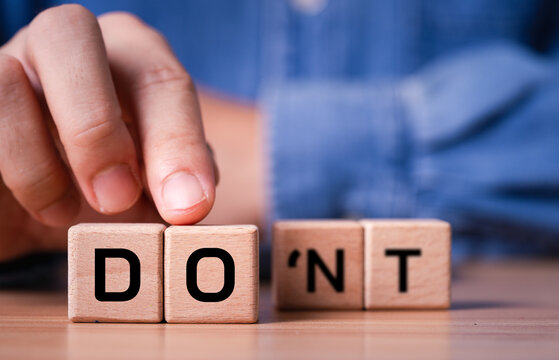 Hand choosing DO over DON'T on wooden blocks, symbolizing decision making, motivation positive mindset, confidence action, choice, determination, courage and overcoming hesitation to achieve goals.