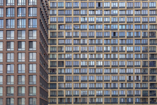 Modern building facade with multiple windows as an urban pattern. Residential apartment skyscraper exterior for real estate background.