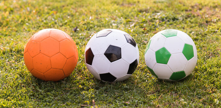 Three Soccer Balls on Green Grass Outdoors