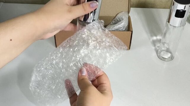 Woman packing fragile glass dishes with bubble wrap for delivery, shipping supplies, protective packaging and e-commerce concept.