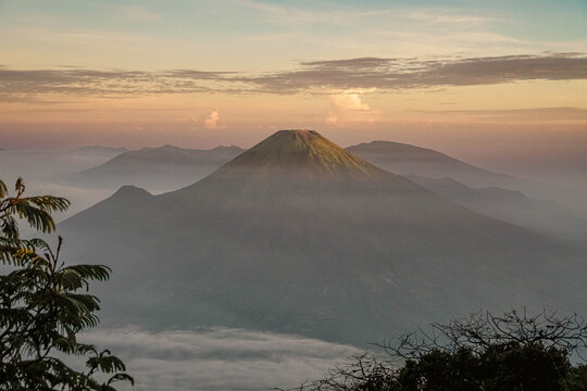 Scenic landscape view of a symmetrical merapi volcano mountain peak during soft golden morning light in Central Java Indonesia