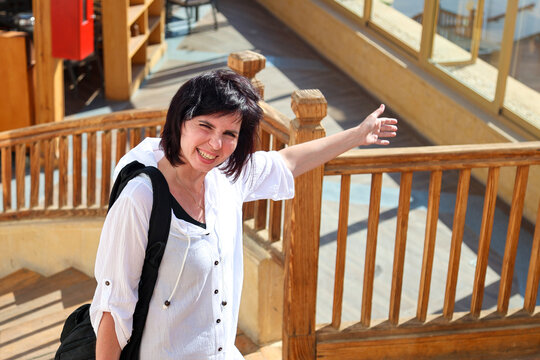Happy female tourist smiling broadly while climbing stairs in a stylish hotel interior.