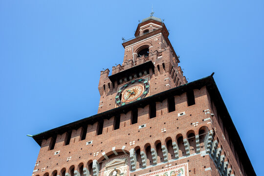 Filarete Tower Clock of Sforza Castle Brick Facade against Blue Sky in Milan City Center Italy.