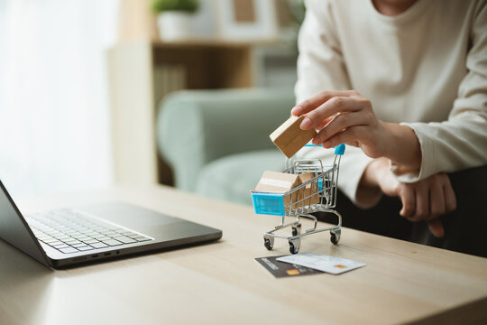 parcel cart checkout with shopping payment; a hand adding a small parcel to a cart. parcel guides buyer choices, cart frames the scene, and checkout adds useful meaning. For useful context.