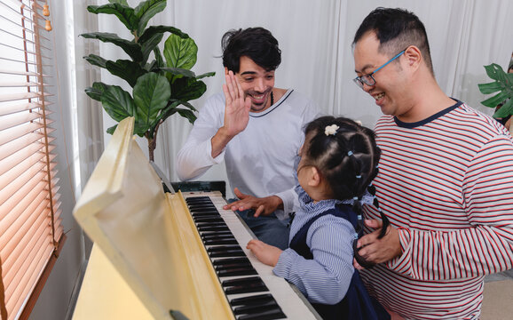 Happy family spending quality time together while learning to play the piano home are helping children practice music creating warm and supportive family environment.