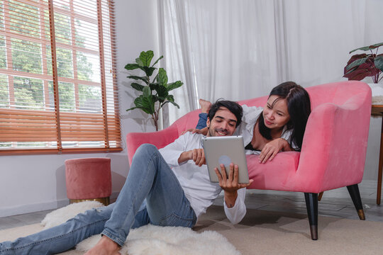 Happy husband and wife relaxing together at home while using tablet and enjoying quality time comfortable sofa.