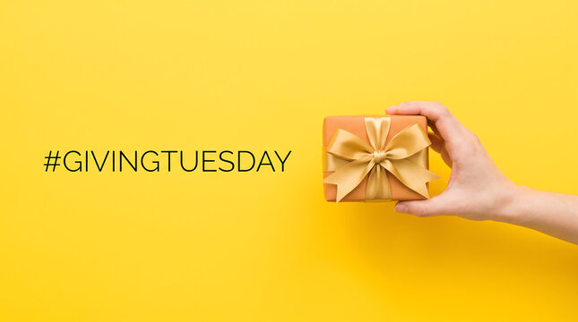 Gift box held by hand featuring golden ribbon on vibrant yellow background for charity giving event
