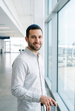 Portrait of smiling Jewish man with kippah near window in modern corporate office building