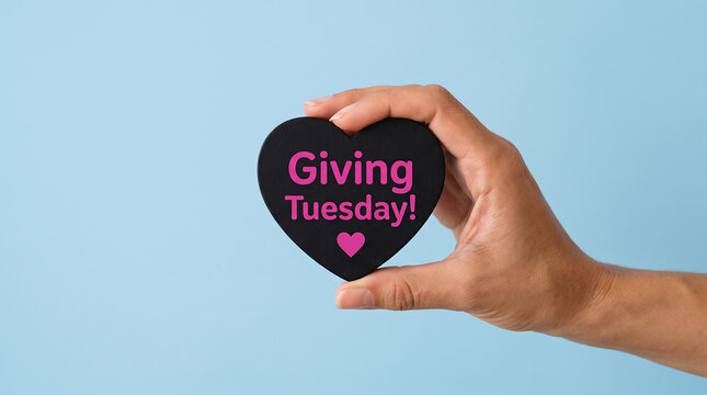 Hand holding black heart shape with Giving Tuesday text isolated on a light blue background