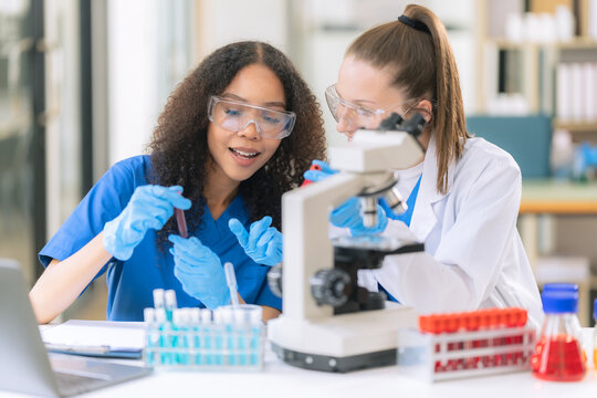 Diverse Female Scientists Conducting Research with Microscope and Chemical Flasks in Laboratory