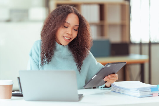 Happy Young African American Woman Using Smartphone at Desk with Laptop and Tablet