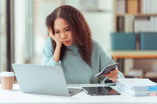 Happy Young African American Woman Using Smartphone at Desk with Laptop and Tablet