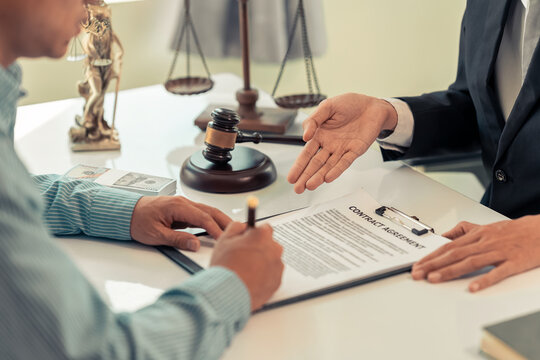 Lawyer and Client Signing Legal Contract Agreement Document in Law Office