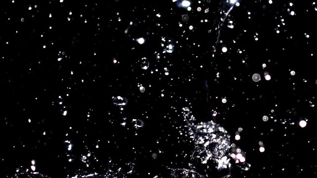 Cinematic water droplets scattering through the air during a powerful slow motion splash.