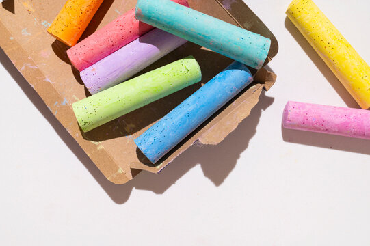 Brightly colored crayons on cardboard packaging against light background with space for text top view. Crayons for drawing, crafts, and school supplies.