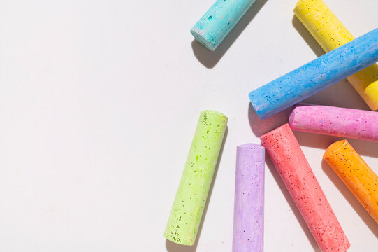 Multicolored crayons scattered on light gray background top view with space for text. Crayons for drawing and creativity, school and preschool materials for fine arts and learning. 