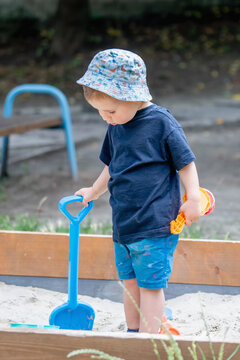 Little boy spending leisure time playing with sand in the backyard.