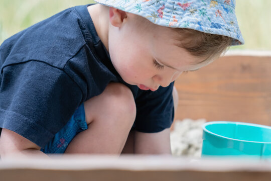 Little boy discovering textures while playing with sand and toys.