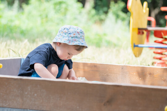 Toddler enjoying creative sandbox activities on a bright summer day. Copy space for text or design.