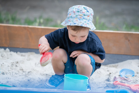 Toddler learning through sensory play with sand in a sandbox.