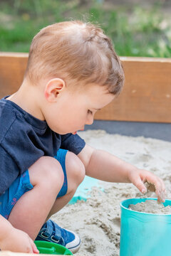 Little boy digging and exploring sand during outdoor playtime.