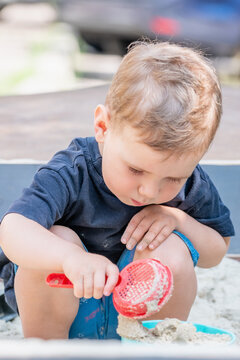 Child practicing coordination while lifting a bucket filled with sand