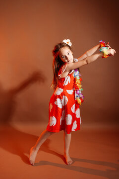 Pretty 6 years old girl in red dress with flowers is dancing in the photo studio with brown background. This photo has been taken in Prague, Czech Republic, August 2025