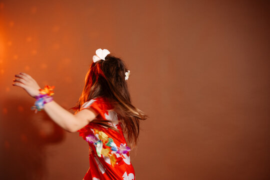 Pretty 6 years old girl in red dress with flowers is dancing in the photo studio with brown background. This photo has been taken in Prague, Czech Republic, August 2025