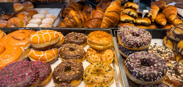 Colorful assortment of glazed donuts and flaky croissants in a bakery display case