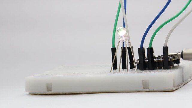 Breadboard wired with jumper cables powers 4 pin RGB LED that glows different colors
