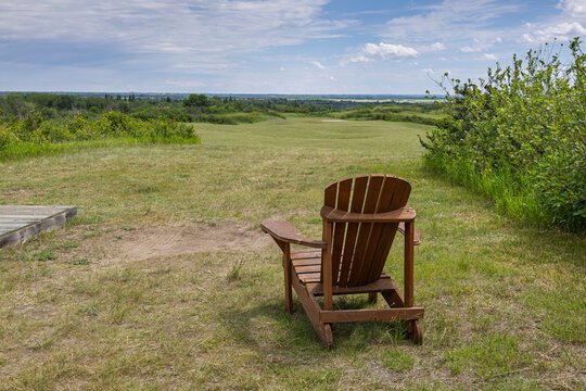 Wooden Adirondack Chair Overlooking Sand Greens Golf CourseUnder a Blue Sky in Pike Lake Provincial Park in Saskatchewan, Canada