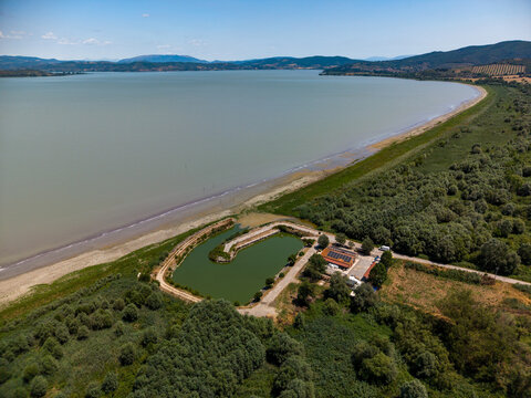 Aerial view of the Cooperativa fra Pescatori Stella del Lago facility with a small pond and buildings on the shore of Lake Trasimeno in Castiglione del Lago, Umbria, Italy.