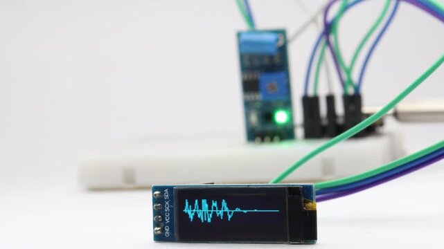 Vibration sensor module on a breadboard triggers wave patterns on an OLED display when tapped. Testing the electronic sensor modules